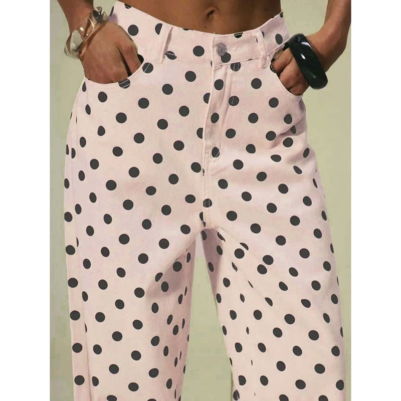 Pink pants with black polka dots worn by a person on a light green background