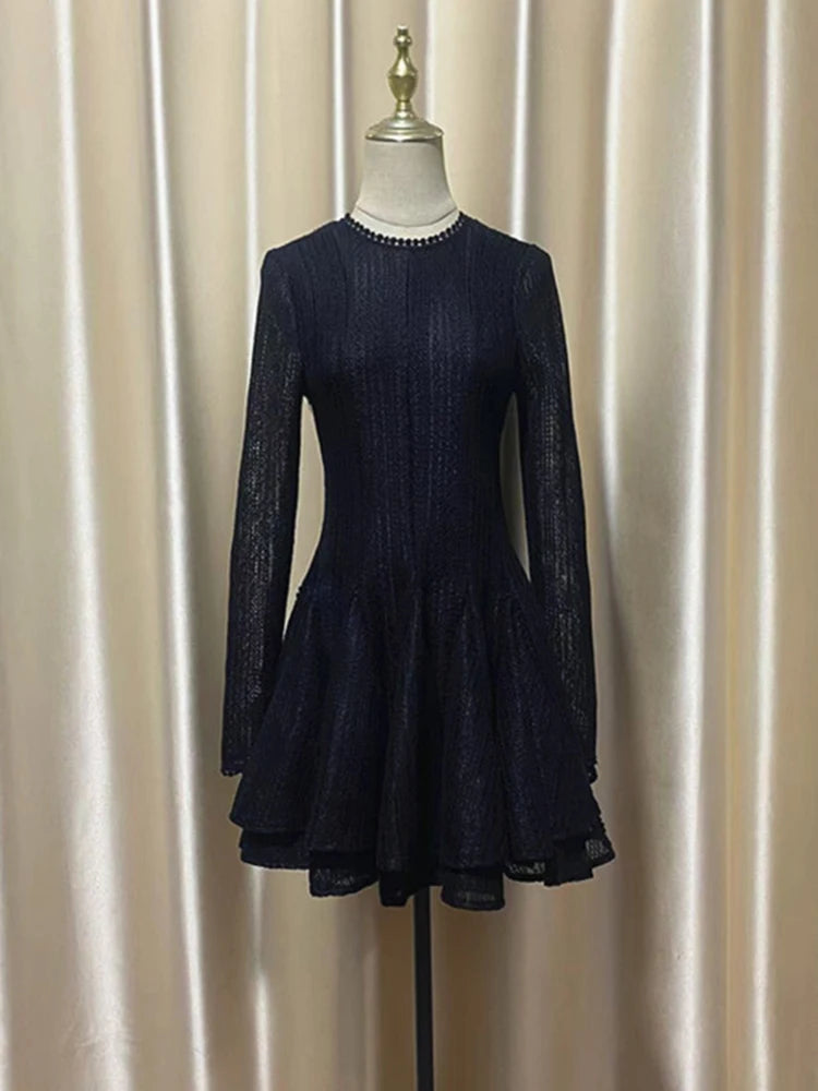 Navy blue dress on a mannequin against a beige curtain background