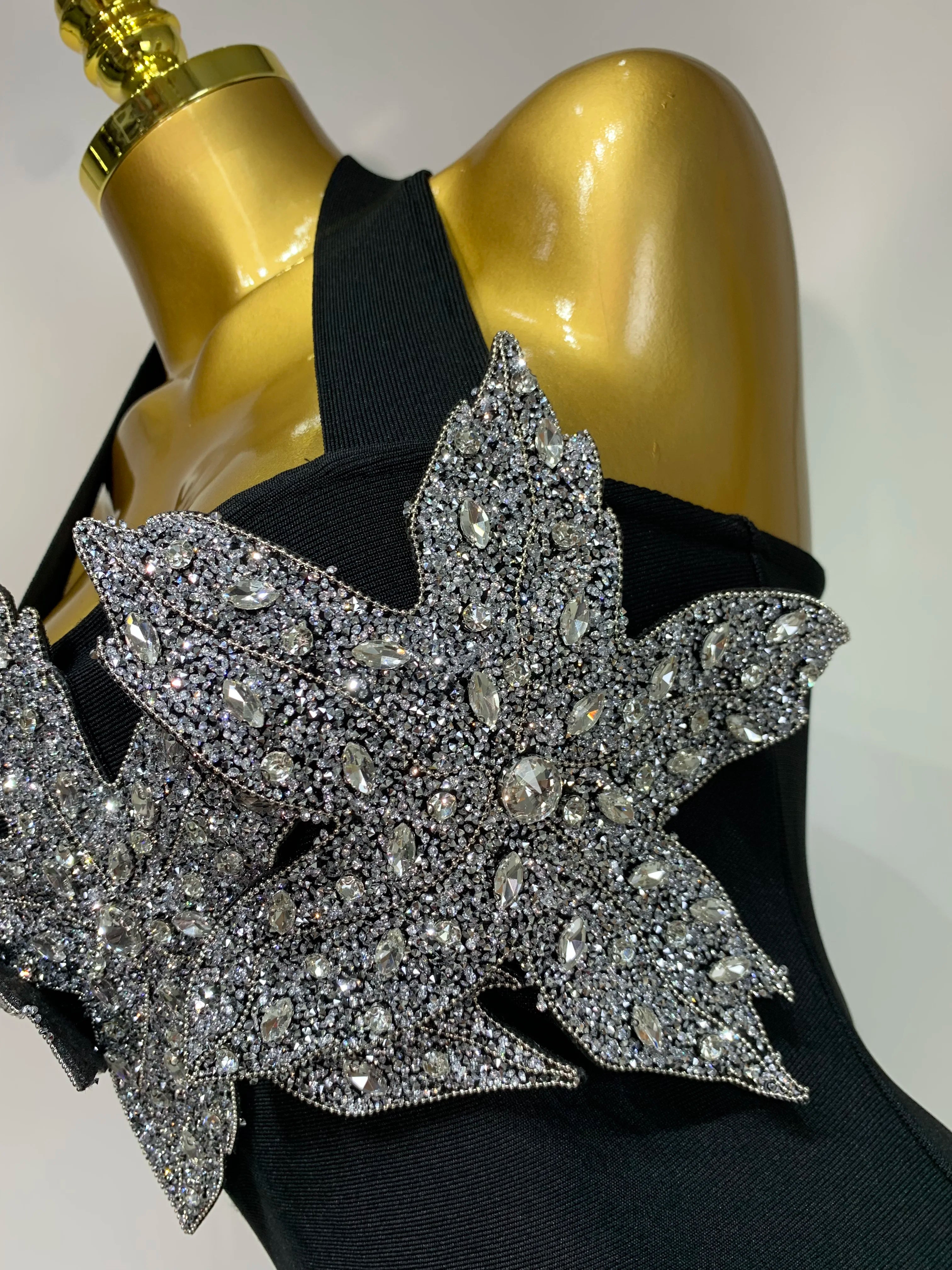 Black top with silver leaf embellishments on a mannequin against a neutral background