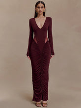 Woman wearing a burgundy evening gown with a deep neckline and ruched design on a beige background