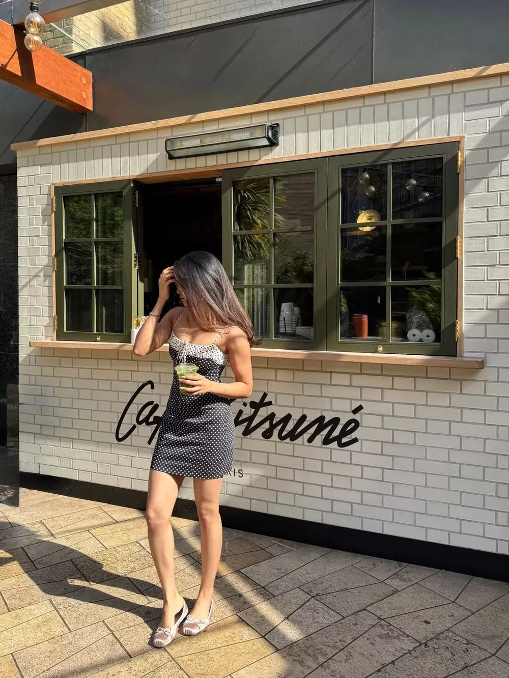 Woman holding a drink in a polka dot spaghetti strap mini dress