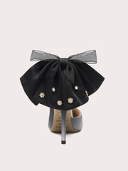 Black bow shoe with decorative elements on a light gray background
