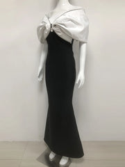 Mannequin wearing a black evening gown with a silver bow detail on a white background