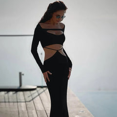 Woman wearing a black cut-out dress standing on a dock with water in the background