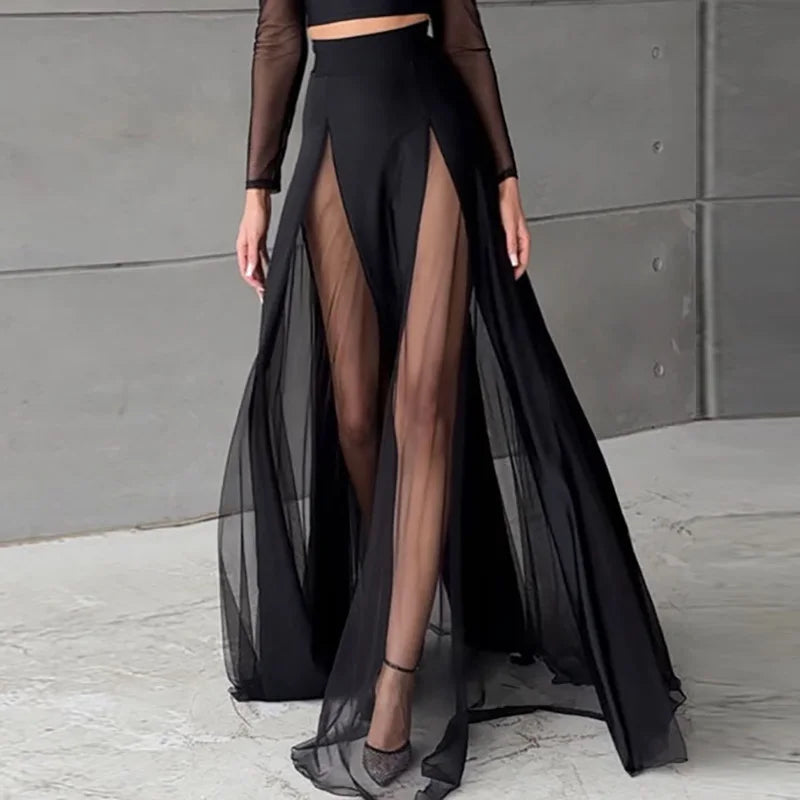 Black sheer skirt with mesh panels worn by a person against a gray concrete wall.