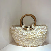 Handbag with wooden handle and shell-like surface on a white background