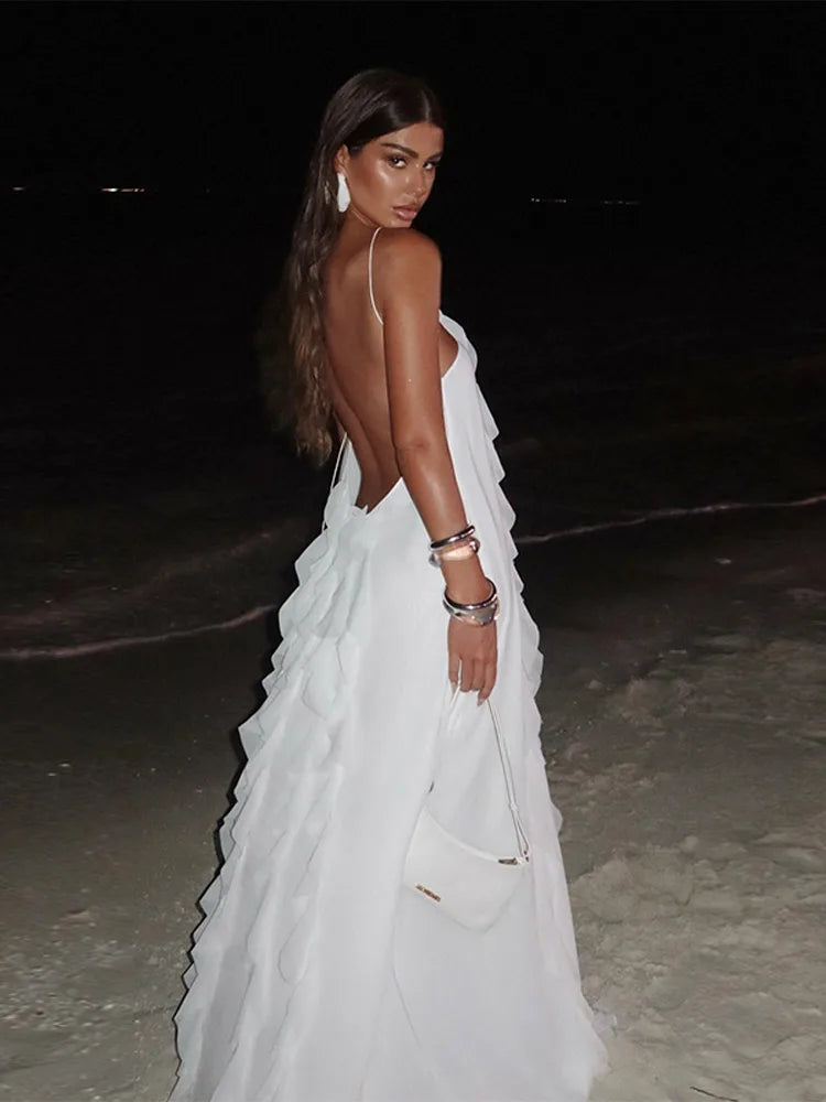 Woman in a white dress standing on a beach at night