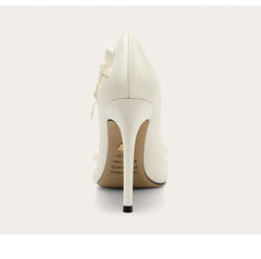 White high-heeled shoe with a decorative bow on a light gray background