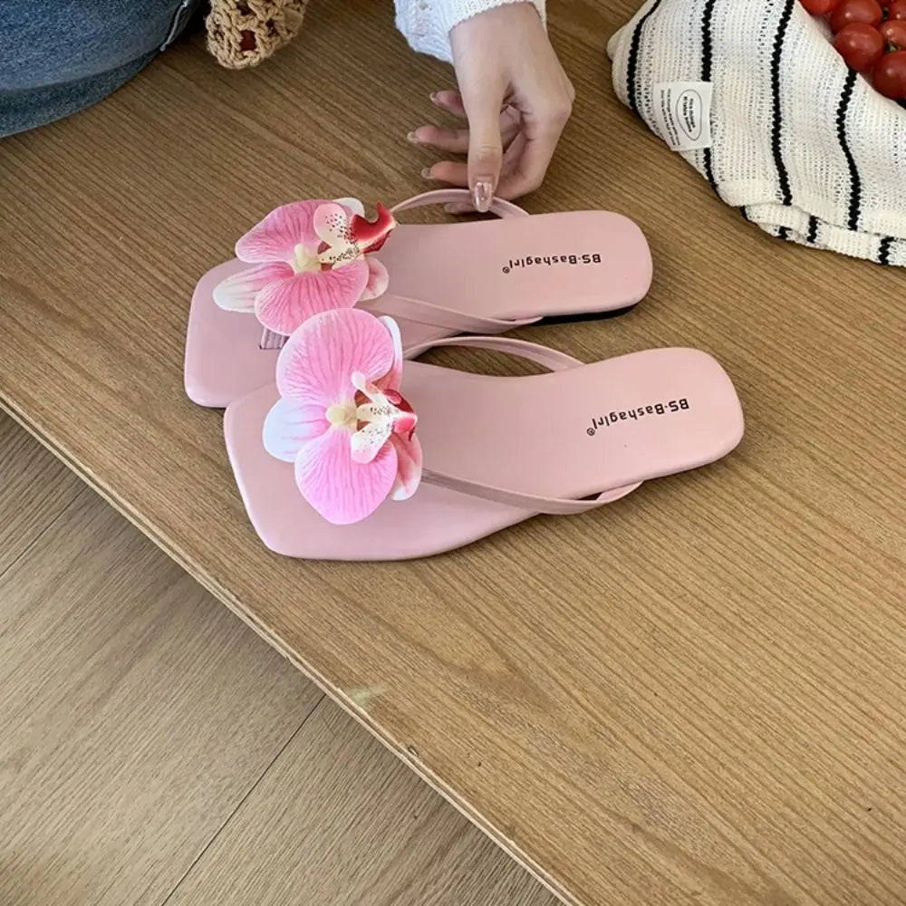 Pink sandals with floral decorations on a wooden surface