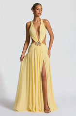 Woman wearing a yellow evening gown with a high slit on a white background