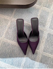 Pair of purple high-heeled shoes on a patterned carpet