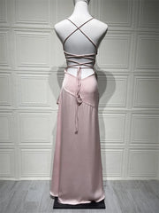 Pink evening gown with criss-cross straps on a mannequin against a gray paneled wall.