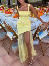 Woman in a yellow dress standing in front of a decorated table with fruits.