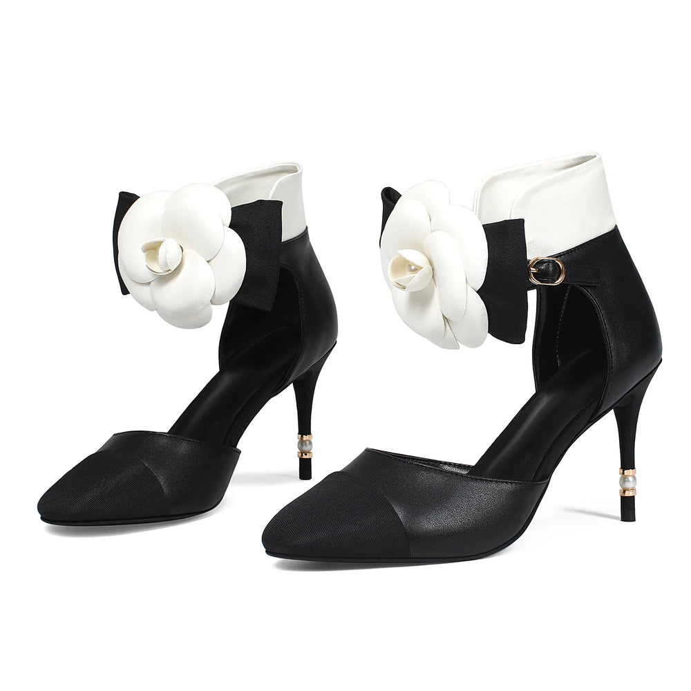 Black high-heeled shoes with white floral embellishments on a white background