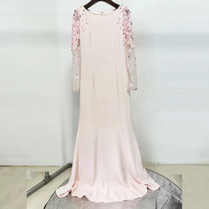 Pink evening gown with floral embellishments on a hanger against a white background