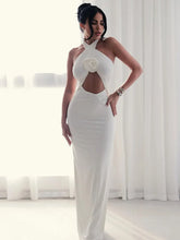 Woman wearing a white evening gown with a floral detail in a bright room.