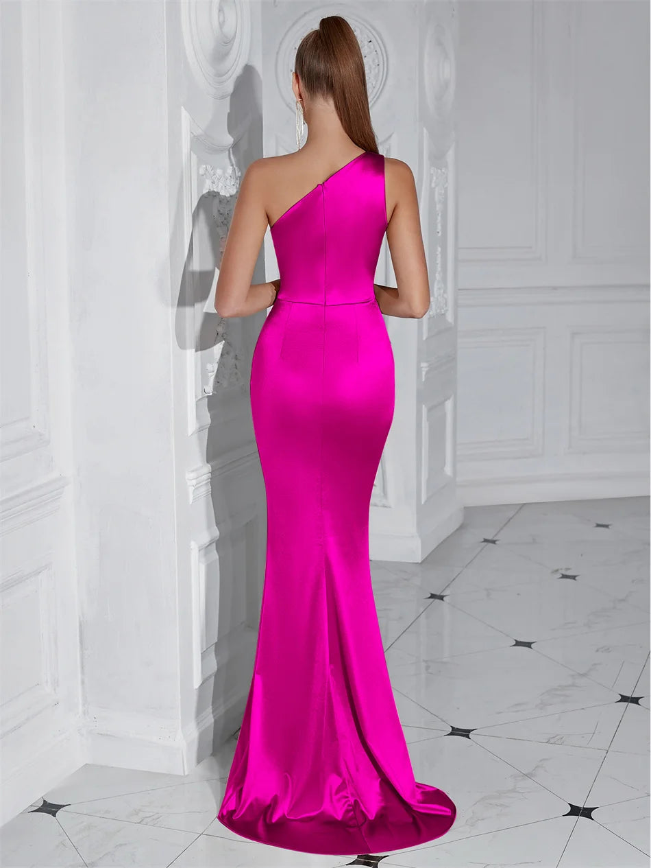 Woman wearing a bright pink one-shoulder evening gown in a white room.