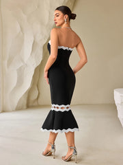 Woman wearing a black dress with white lace details in a minimalistic setting
