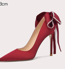 Red high-heeled shoe with decorative bow on a white background