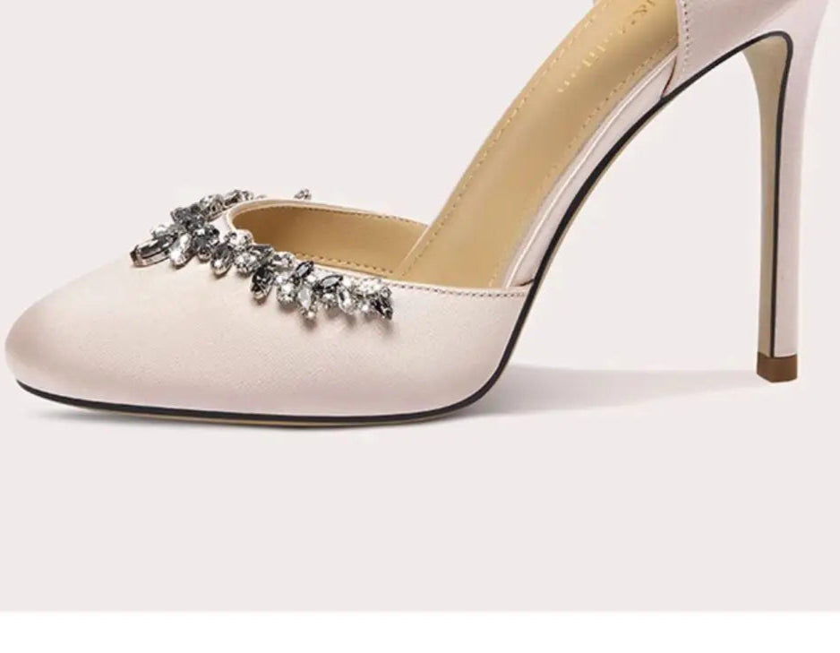 White high-heeled shoe with decorative embellishments on a light pink background