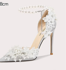 White high-heeled shoe with floral and pearl details on a white background