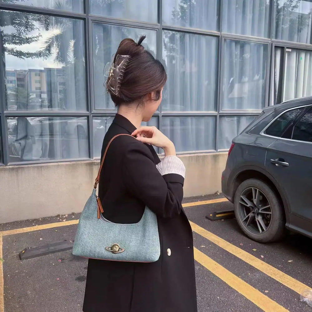 Woman holding a denim handbag in an urban setting