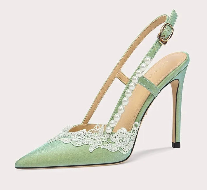 Green high-heeled shoe with lace detailing on a white background