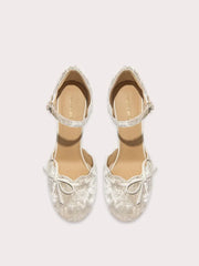 Pair of silver glittery shoes with bow details on a light gray background