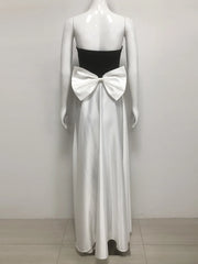 Mannequin wearing a black strapless top and white flowing dress with a large bow on a plain background
