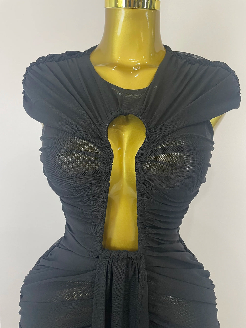 A mannequin wearing a black dress with a unique cutout design on a white background