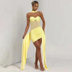 Woman wearing a yellow strapless dress with a high slit on a plain background