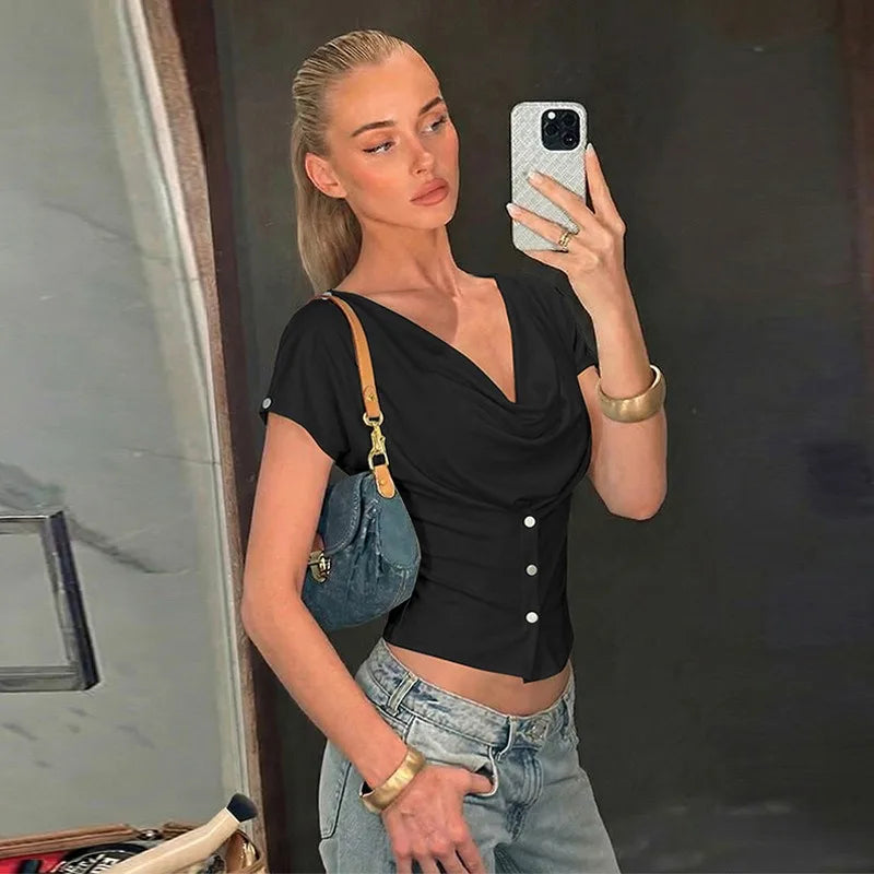 Woman taking a mirror selfie wearing a black top and denim jeans, holding a phone.
