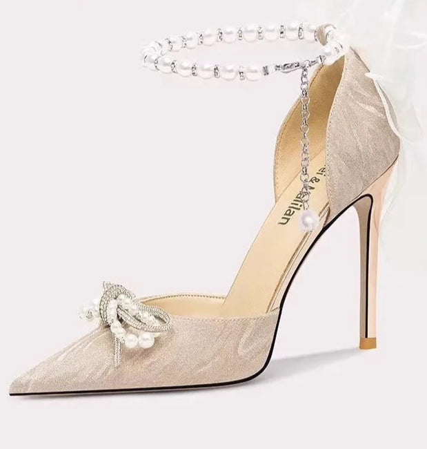 Beige high-heeled shoe with decorative bow on a white background