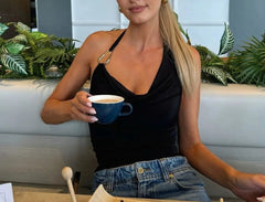 Woman holding a blue mug in a casual setting with plants in the background
