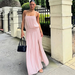 Woman wearing a pink maxi dress with spaghetti straps and a high slit