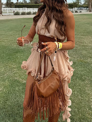 Woman holding a brown fringed handbag in an outdoor setting