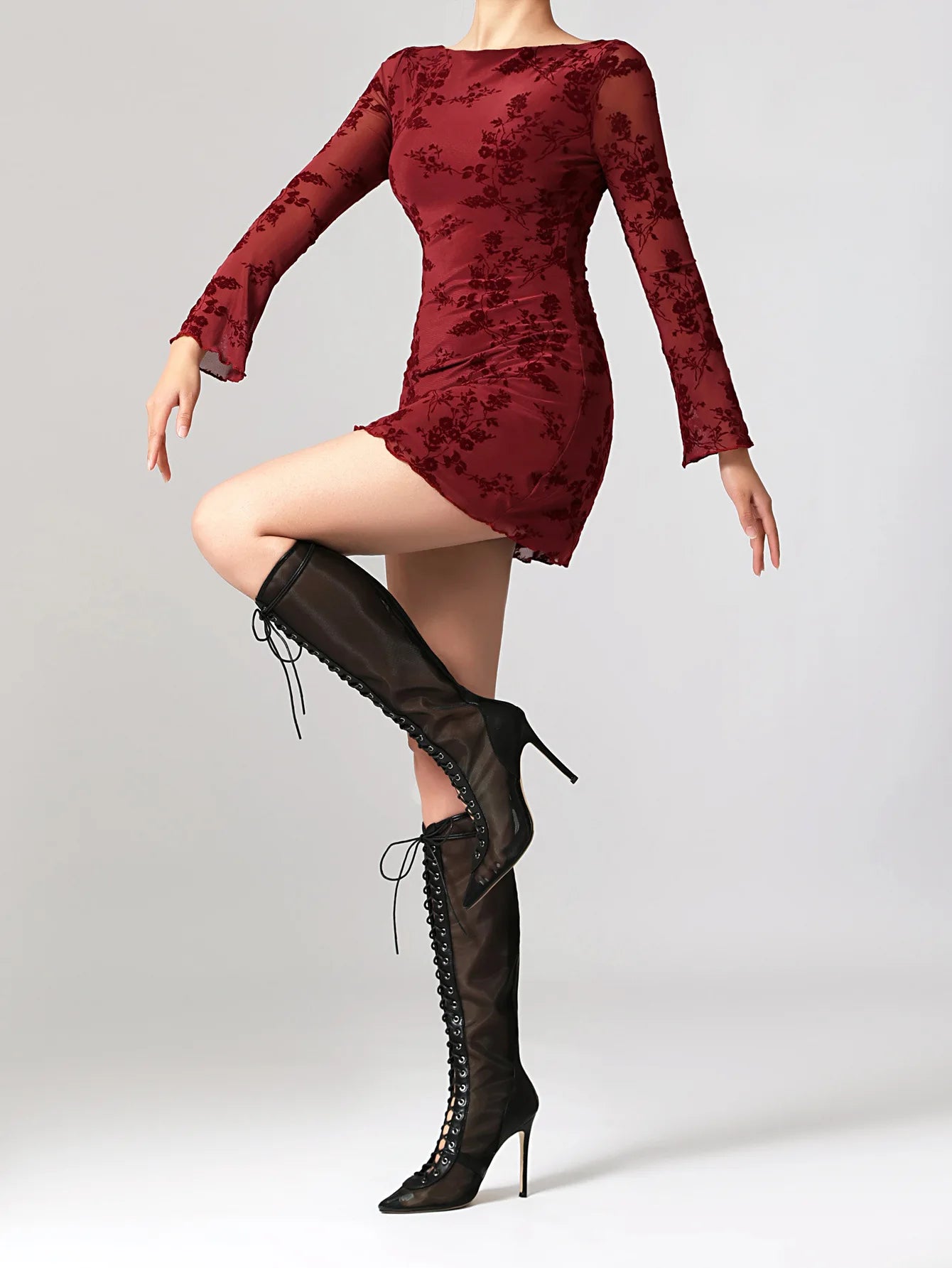 Red floral dress with long sleeves and black knee-high boots on a plain background
