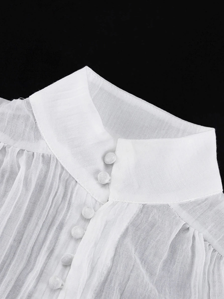 Close-up of a white blouse with fringes and buttons on a black background
