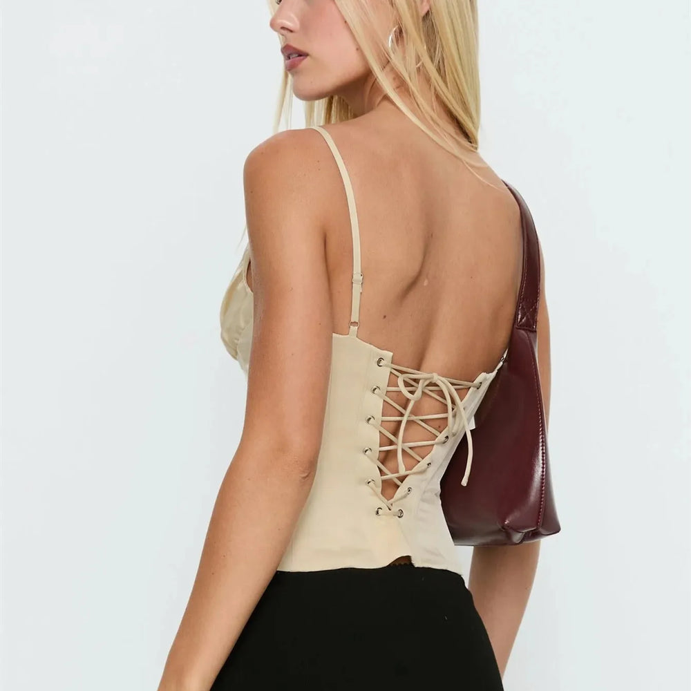 Woman wearing a beige lace-up top with a plain background