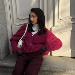 Woman wearing a red sweater and maroon pants sitting on steps.