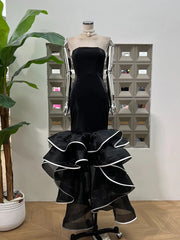Black strapless dress with ruffled layers on a mannequin against a neutral background