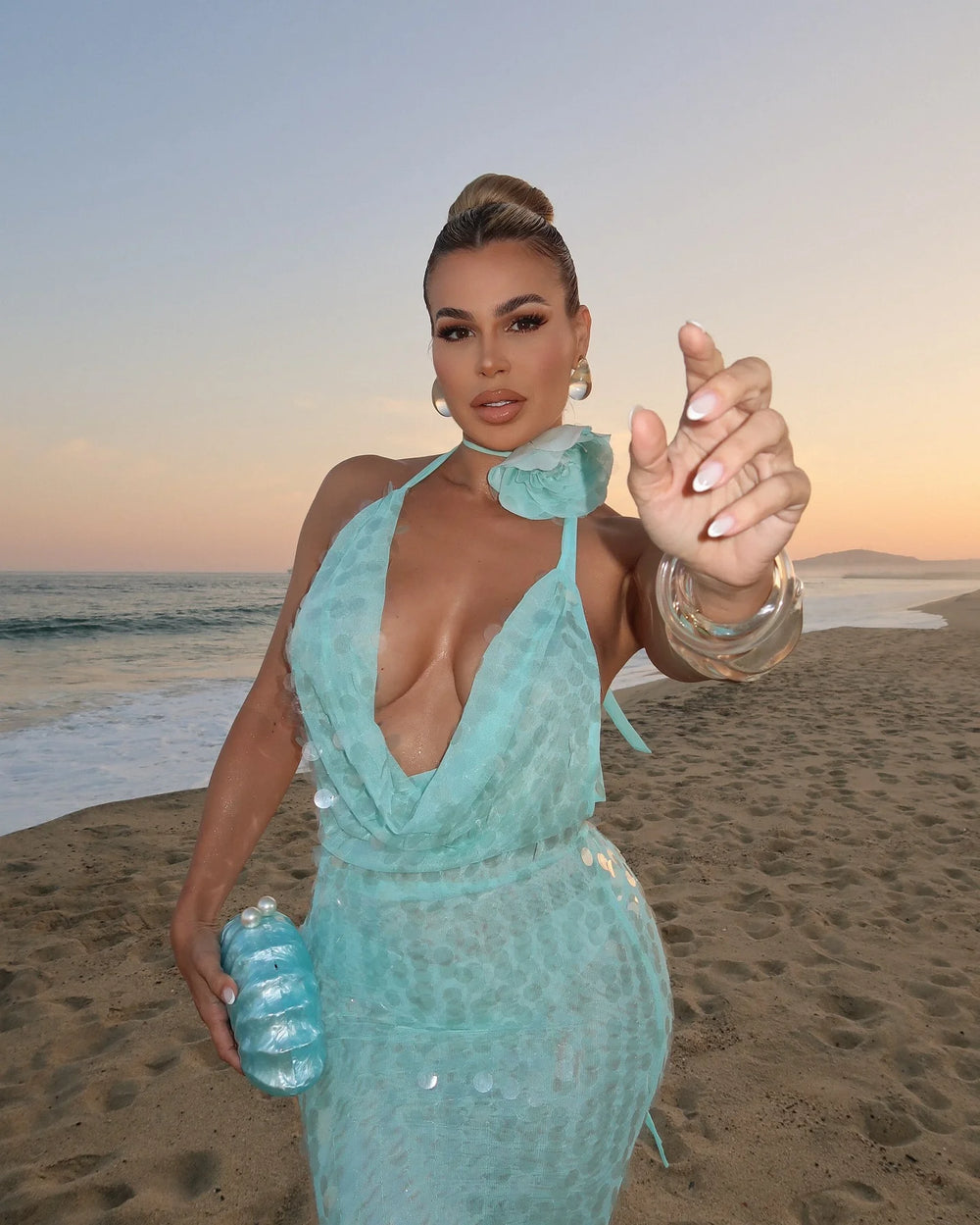 Woman in a teal dress on a beach at sunset