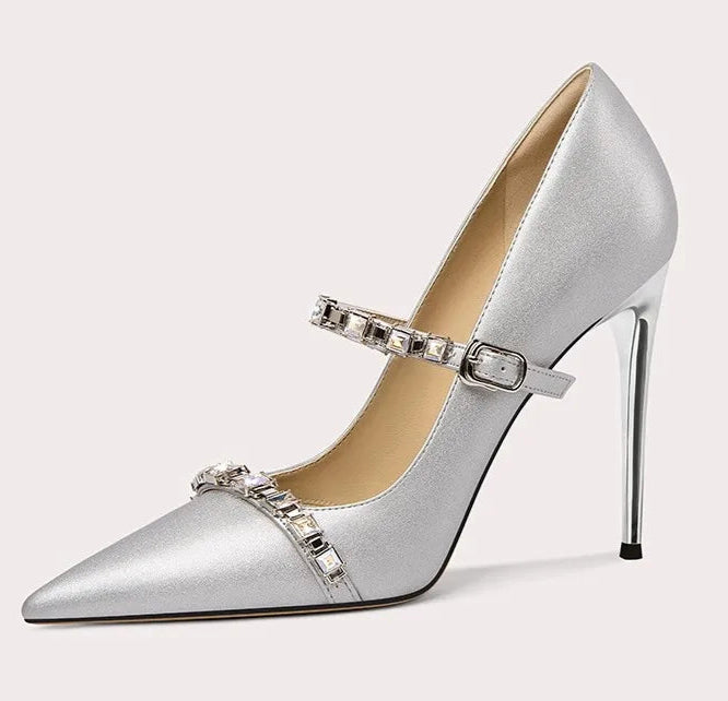 Silver high-heeled shoe with decorative strap on a light gray background