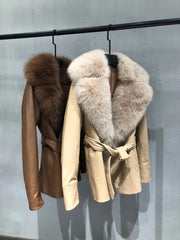 Two leather jackets with fur collars hanging on a rack against a gray background.