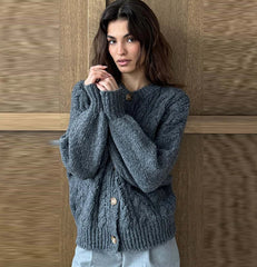 Woman wearing a blue knitted sweater against a wooden panel background