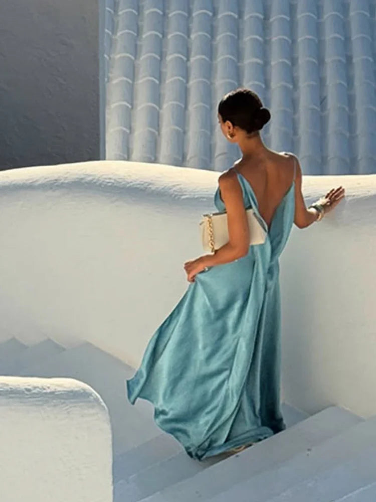 Woman in a blue dress sitting on a white ledge with a blue tiled wall in the background
