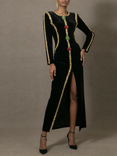 Black dress with gold trim and floral embellishments on a gray background