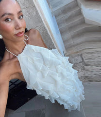Woman holding a white ruffled handbag in an outdoor setting