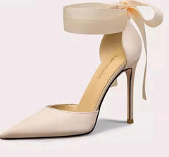 Beige high-heeled shoe with ribbon on a light pink background