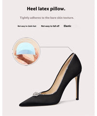 Black high-heeled shoe with heel latex pillow feature on a light gray background